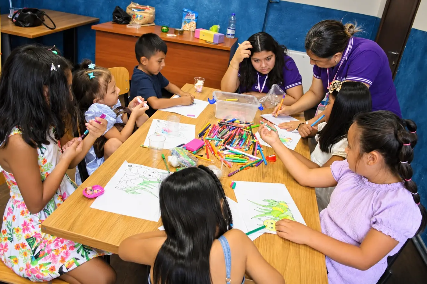 Bambini che colorano al tavolo con le maestre durante la Scuola Biblica